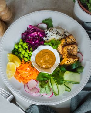 Our New Vegan Buddha Bowl: Marinated baked sesame tofu, edamame beans, jasmine rice, ginger cabbage pickle, raw cucumber and radish served with fresh leaves and peanut miso sauce  at Miranda Cafe in North London