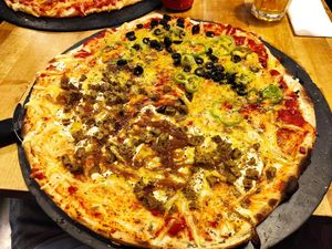 Pizza vegana, media tomate, queso vegano, seitán casero, cebolla caramelizada y mostaza; mitad de tomate, queso vegano, falafel, pimiento verde, salsa de curry y aceitunas negras at Pizzeria Trozo in Bilbao