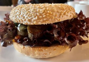 Bagel mit mit gegrillter Tomate, veganem Reibeschmelz, Feigensenf, Antipasti, Salat  at Zum Scheele in Stralsund