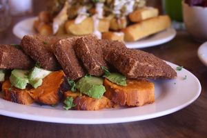 Shnizalonim Crispy battered smoked tofu coated with a mix of toscana spices & crunchy gluten-free crumbs, accompanied by sliced yam & avocado. at Chickpea Restaurant in Vancouver