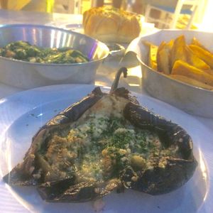 Eggplant dip without onion, finely presented in the veggie itself, sauté greens and onion, fresh potato wedges and garlic bread with olive oil. All vegan  at Caldera Taverna Bar in Rhodes