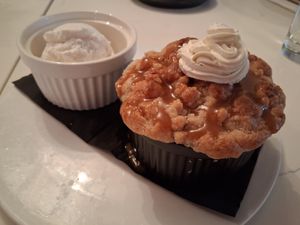 Peach Cobbler: fresh peaches, buttery crumble topping served with cashew caramel & whipped cream plus a side of ice cream at P.S. Kitchen in New York City