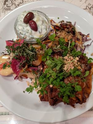 Lasagna made with nutitional yeast, nuts, lentils.  Sides are slaw with ginger vinaigrette, cucumber salad, and a tomato and onion salad at Atlas Bar in Copenhagen