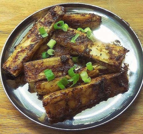 Spicy mogo/cassava chips tossed in a special homemade tamarind sauce and topped with spring onions at Jaldee Jaldee in Brighton