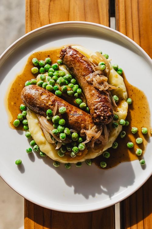 BANGERS (GF) - BEEF SAUSAGES + PUMP + MASH + PEAS +GRAVY  at Crate Cafe in Canggu