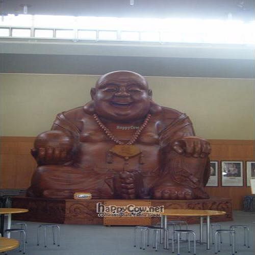 The giant wooden Buddha in the hall next to the restaurant building at SaiShokuKenBi in Tokyo