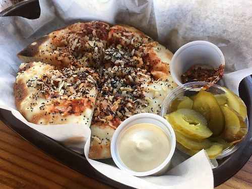 Onion flatbread served with tahini sauce, pickles, & chili sauce.  at Frena Bakery and Café - Soma in San Francisco