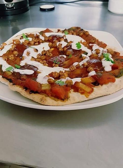 Our Crunchy Indian pizza with a creamy masala sauce, roasted chickpeas, mint soy yoghurt and mango chutney  at Beans and Greens in Whitehaven