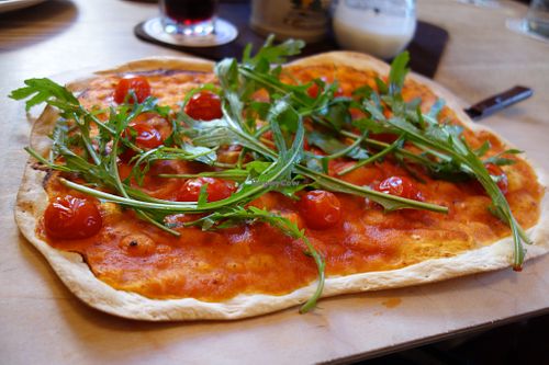 Flatbread with tomato sauce, cherry tomatoes, and rocket leaves, plus garlic (vegan) at Tante Paula im Mailkeller  in Rosenheim