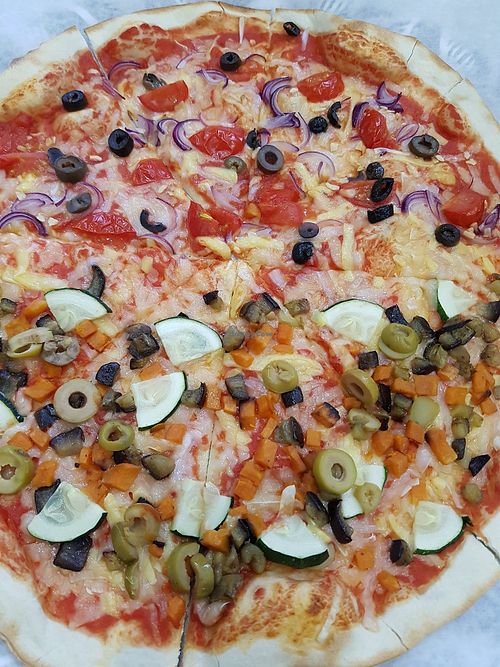 Left side with red onions, black olives, cherry tomato and garlic. Right side with sweet potato, grilled aubergine, zucchini, green olives. Both of sides with the 3 types of vegan  at Agvania Pizza in Limassol