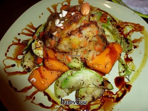 Vegan burger served on a bed of baked root vegetables, sprinkled with almonds.   at Earth Cafe - Derb Zawak in Marrakech
