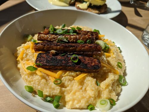 Creamy cheesey grits topped with scallions, crispy tempeh bakun at Verdine in Houston