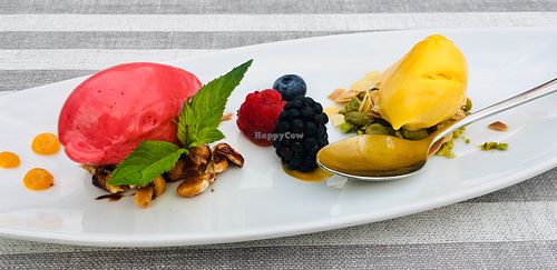 Raspberry sorbet, mango sorbet on caramelized peanuts, almond slivers and pistachios. Decorated with fresh berries at MythenForum in Schwyz