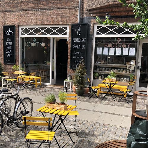 Cozy outdoor seating with herbs at the sunny-coloured furnitures and homegrown tomato plants. at Rooty in Copenhagen