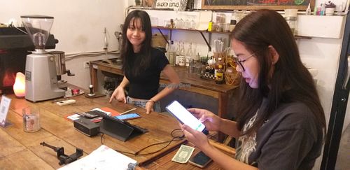 Nita (left) looks on while Net(right) helps me set up my smart card phone service  at Sacred Lotus Cafe in Phnom Penh