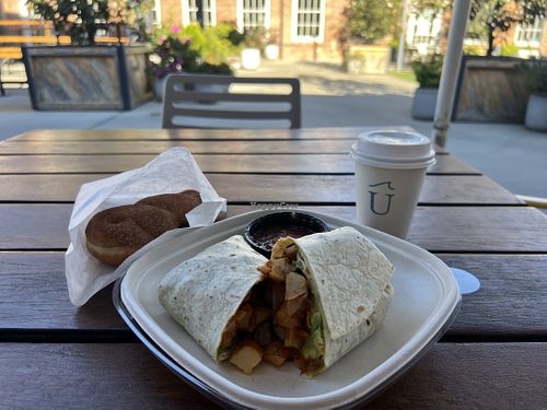 Vegan breakfast burrito and oat milk cappuccino. (The cinnamon twist in the bag is from another vendor nearby in the Hall).   at Undercurrent Coffee - Optimist Hall in Charlotte
