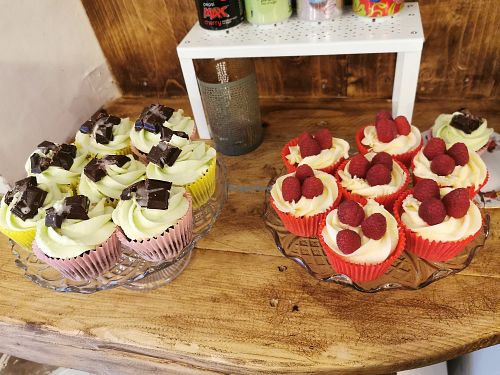 On the left are chocolate cupcakes with peppermint icing and mint chocolate on top, on the right are vanilla cupcakes with a raspberry jam centre, vanilla frosting and raspberries  at Not Just Desserts in Mansfield