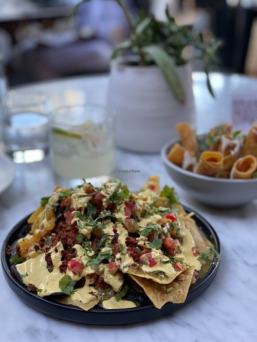 Chorizo Nachos with Taquitos in the background at Gracias Madre in Newport Beach