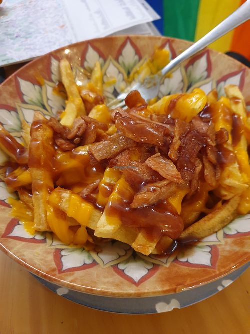 Cheesy fries comes with bacon bits not listed on menu at La Vegana Taperia in Malaga