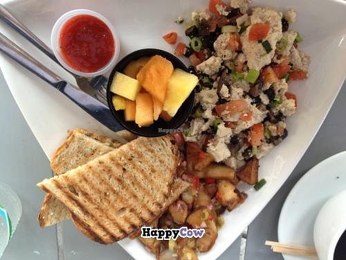 Tofu scramble with tomatoes, mushrooms and scallions. Served with toast, fruit cup (pineapple and cantaloupe) and breakfast potatoes. at The Cafe at Books and Books in Miami Beach