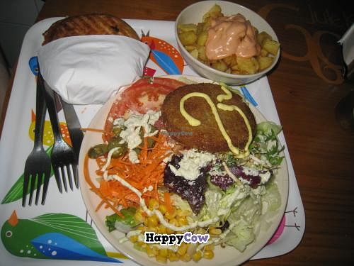 Burger in bun (served in a napkins so easy to eat on the go) and burger and salad (served on a plate with cutlery) at Gopal - Vegan Deli in Barcelona