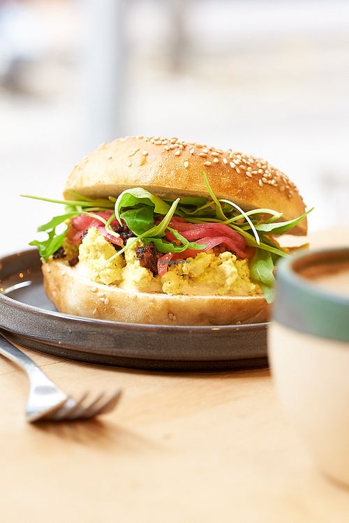 Seasonal bagel with scrambled tofu, tempeh bacon, rocket, red onion pickled at NEØ Coffee House in Barcelona