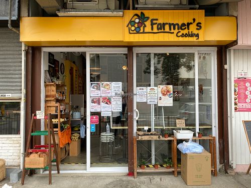 Shop exterior and posters showing lunch sets and product highlights, including vegan options at Farmer's Cooking in Hong Kong Island