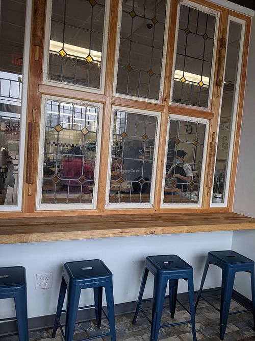 Counter seating with repurposed antique windows & rolling pins allowing views into bakery work area at Sinfull Bakery in Houston