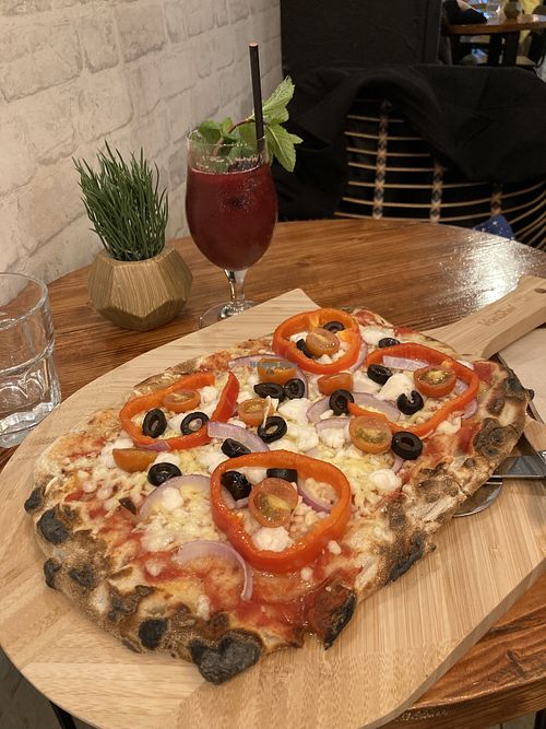 Very delicious and filling Greek pizza with Vegan Up juice  at Nomas in Macclesfield