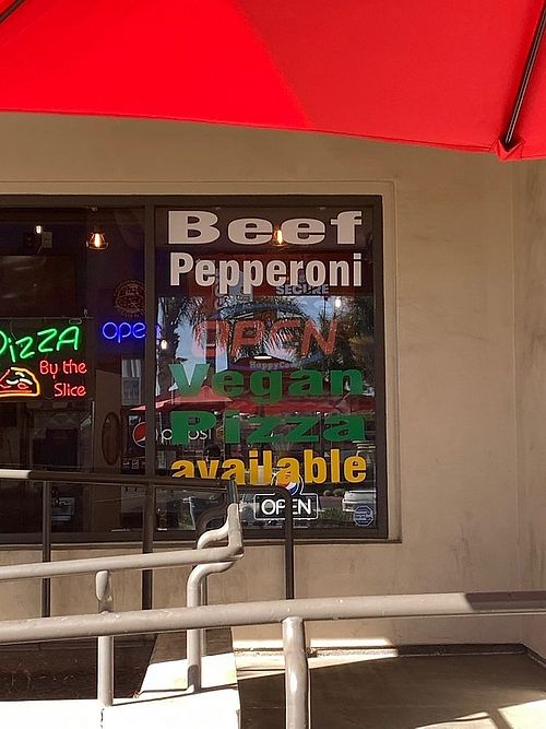 Signage on restaurant window promoting vegan pizza at University Pizza Company in Riverside