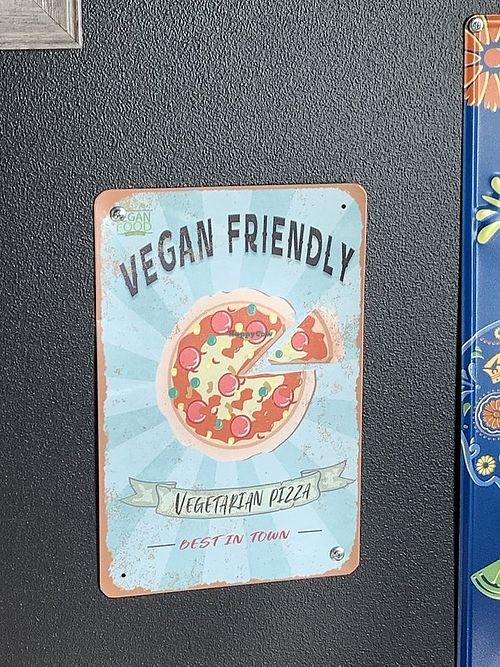 Signage inside restaurant promoting vegan friendly options available at University Pizza Company in Riverside