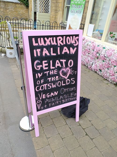 Outside sign showing Vegan options 🙂 at Fairy Gelato & Cakes Lora Nova in Bourton-on-the-water
