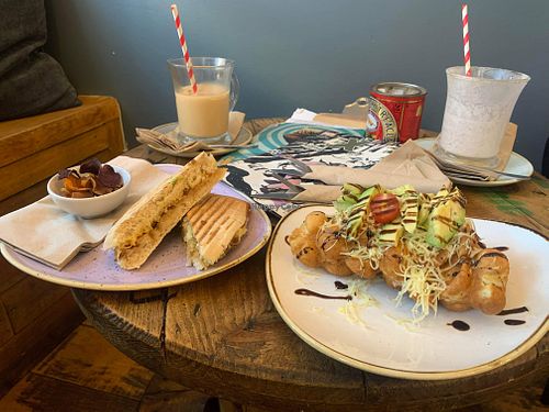Vegan cheese and onion chutney panini and “the vegan one” waffle. Oat milk pumpkin spiced iced coffees at the back    at ComiCoffee in Newport