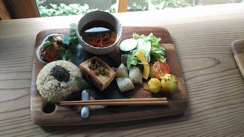 A platter of small dishes served on a chopping board. The sprouted rice served with sesame is delicious on its own! at Yasai Cafe Meguri in Nikko