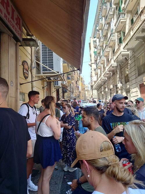 Behind the guy with white t shirt next to the girl with blue skirt is the line for take away at Pizzeria da Michele in Naples