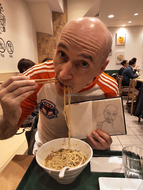 Me eating ramen in T's holding a sketch I did of myself from a photo of me eating ramen in T's.  at T's Tantan - Tokyo JR Station in Tokyo