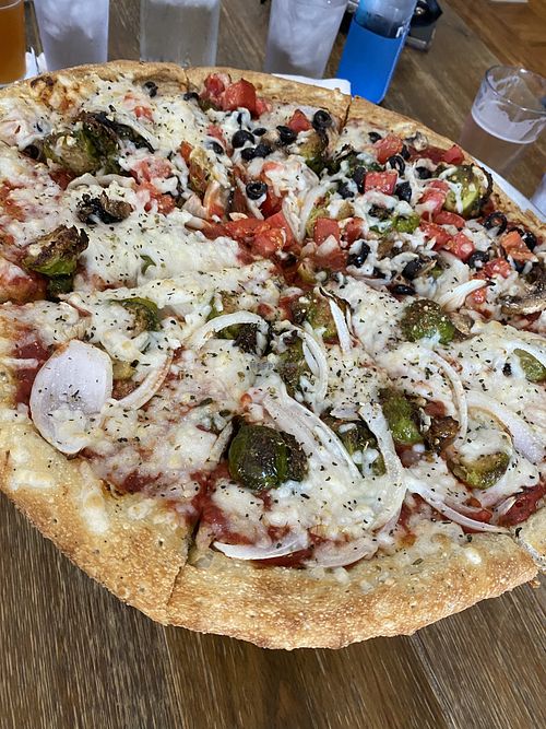 Vegan pizza with onion and Brussel sprouts on half, tomatoes, black olives, mushrooms and Brussel sprouts in the other half. Uses Follow Your Heart Cheese    at Dead Low Brewing in Cincinnati