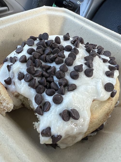 Roll with orange icing and chocolate chips (missing one bite).  at Cinnaholic in Raleigh
