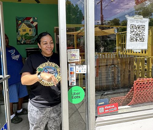Chef Lulu adding Happy Cow sticker to window!   at Casa Borinqueña in San Francisco