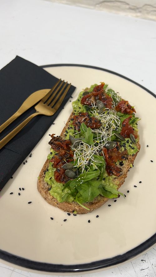 Tostada con aguacate, hojas verdes y tomates secos.  at Malament in Barcelona