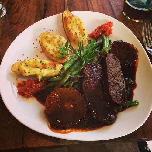 Homemade seitan medallions with stuffed potatoes, green beens and orange and rosemary sauce. at Bistro Bardot in Berlin