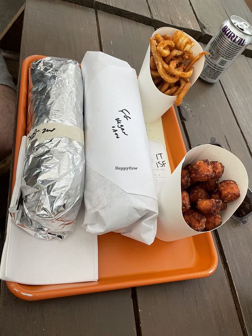 Huge falafel sandwich (white paper) with side of curly fries and sweet potato tots  at Eastcut Sandwich Bar in Durham