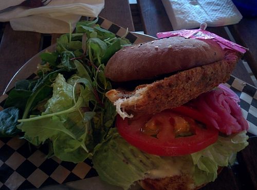 Spicy chicken burger; crispy fried chicken, cranberry chutney, jalapeño aioli, pickled red onions, romaine, tomato, house baked bun with side salad at Hella Vegan Eats in Oakland