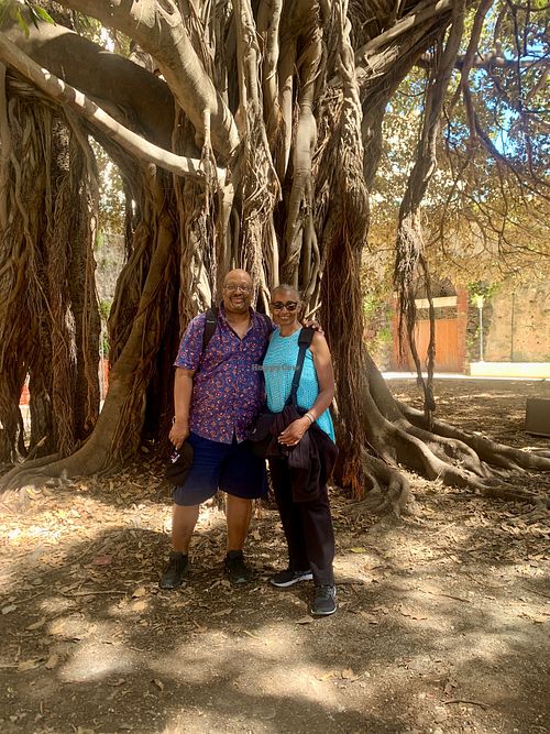 Bert & Yvonne in the shade of the ficus tree. - May 2024 at Vegan Food Tour Ortigia in Siracusa