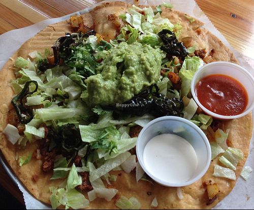 Peppers at the Gates of Dawn special: spicy seitan sausage, lettuce, guac, fried poblano peppers, papas, salsa & sour cream atop a fried tortilla! at Green New American Vegetarian in Tempe
