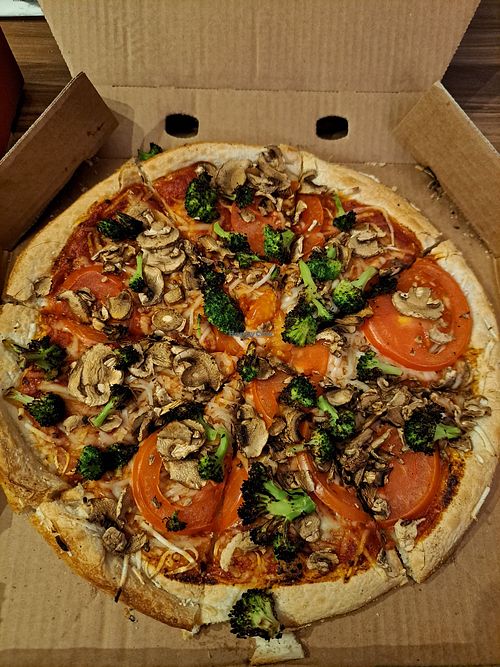 Pizza with broccoli mushrooms tomatoes and vegan cheese at Domino's Pizza in Hamburg