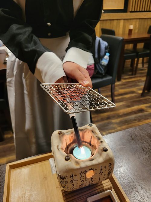 Waitress starting the fire at Komaki Shokudo in Tokyo