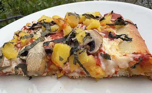 2 slices of 10” Vegan grandma pizza with mushrooms & pineapple with thin julienned slices of fresh basil on top.  at Genova Pizza in Audubon