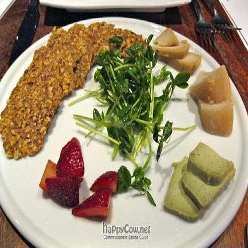 Plate Of Assorted Cultured Dr. Cow Tree Nut Cheeses and Rosemary Crisps with wild huckleberry compote, mustard greens. at Pure Food and Wine in New York City