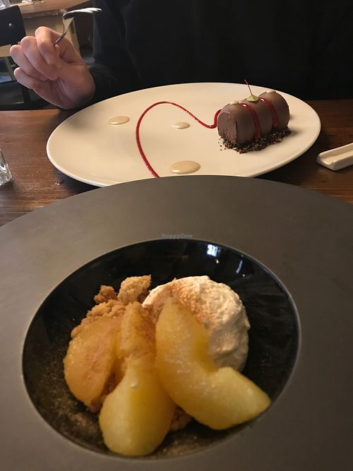 Desserts: baked apple with coconut cream and almond cookie crumbles, and raw chocolate cake.  at Soul Kitchen - Creatività Vegetale in Turin